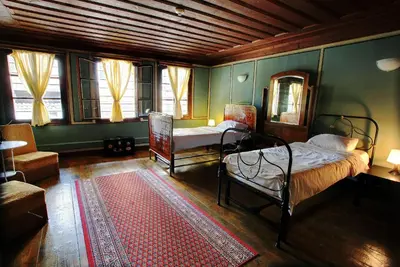 a bedroom with two beds and a chair and a rug at Guest House Old Plovdiv in Plovdiv