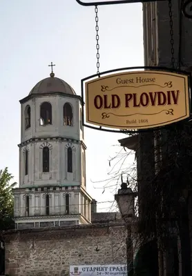 a sign in front of an old building with a clock tower at Guest House Old Plovdiv in Plovdiv