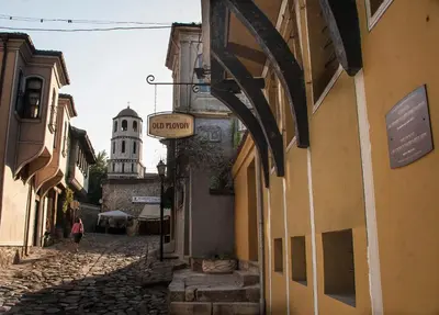 a woman walking down a street with a sign on a building at Guest House Old Plovdiv in Plovdiv