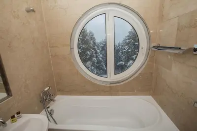 a bathroom with a tub and a round window at Family Hotel Saint George in Sofia