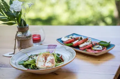 a table with a bowl of salad and a plate of food at Family Hotel Saint George in Sofia
