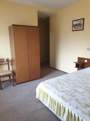 a bedroom with a bed and a cabinet and a chair at Guesthouse Kiritsovi in Bansko
