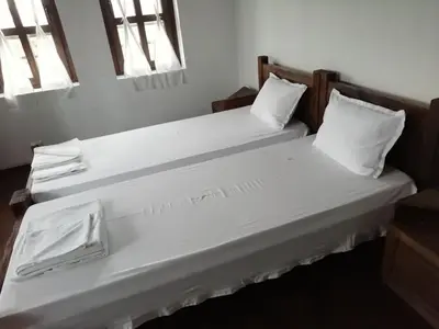 two beds with white sheets and pillows in a room at Family Hotel Kalifer in Kalofer