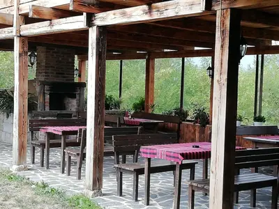 a wooden pavilion with tables and benches and a fireplace at Family Hotel Kalifer in Kalofer