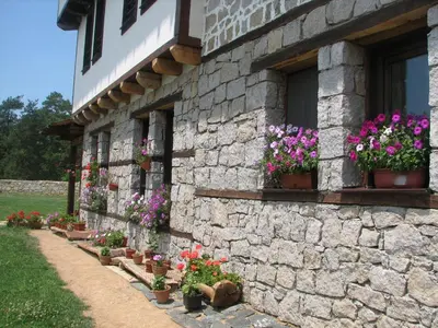 a stone building with potted plants and flowers on it at Family Hotel Kalifer in Kalofer