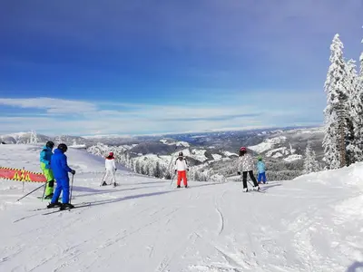 a group of people skiing down a snow covered slope at Grand Monastery - Azure Apartment in Pamporovo