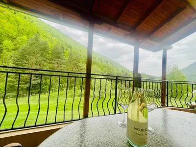 a table with two wine glasses on a balcony at Family Hotel Gorski Kut in Rilski Manastir
