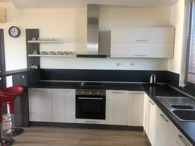 a kitchen with white cabinets and a black counter top at VILLA RELAX in Tsigov Chark