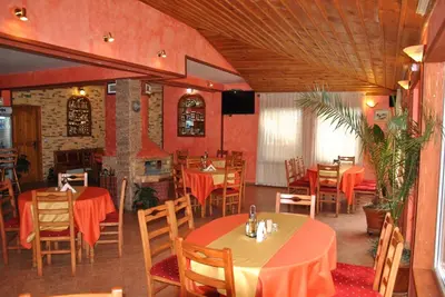 a restaurant with tables and chairs and a fireplace at Family Hotel Shoky in Chepelare