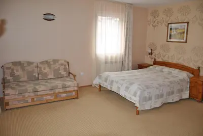 a bedroom with a bed and a chair and a window at Family Hotel Shoky in Chepelare