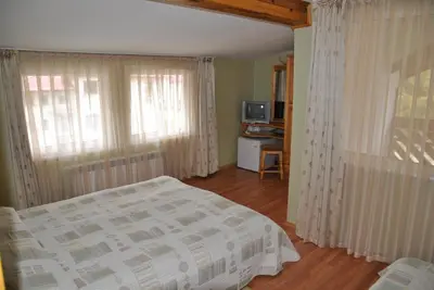 a bedroom with a bed and curtains and a television at Family Hotel Shoky in Chepelare
