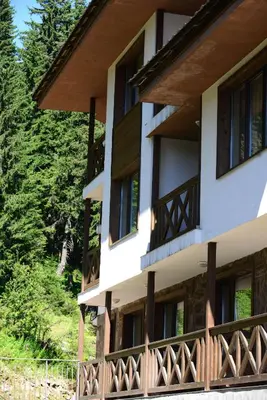 a building with wooden balconies and trees at Hotel Mursalitsa by HMG - Half board in Pamporovo