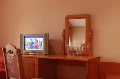 a television sitting on a wooden table with a mirror at Guest House Tabakovi in Velingrad