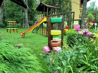 a park with a playground with a slide and flowers at Vila Kalvachevi in Tsigov Chark