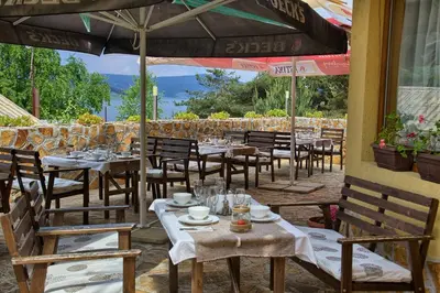 a restaurant with tables and chairs and an umbrella at Guest House Slunchev Cviat in Tsigov Chark