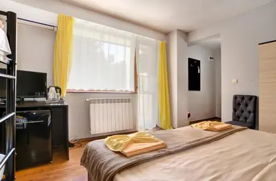 a bedroom with a bed and a window with yellow curtains at Guest House Slunchev Cviat in Tsigov Chark