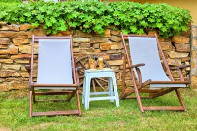 two chairs and a table in front of a stone wall at Guest House Slunchev Cviat in Tsigov Chark