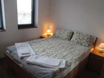 a bed in a bedroom with two lamps on two tables at Gramadeto Complex Alexander Services Apartments in Bansko