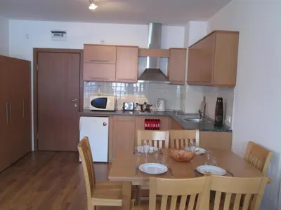 a kitchen with a wooden table with chairs and a dining room at Gramadeto Complex Alexander Services Apartments in Bansko