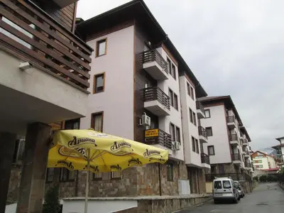 a yellow umbrella in front of a building at Gramadeto Complex Alexander Services Apartments in Bansko