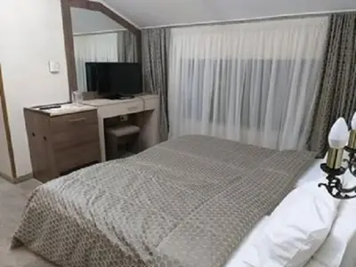 a bedroom with a bed and a desk with a computer at Spa Hotel Kleptuza in Velingrad