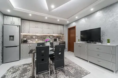 a kitchen with white cabinets and a flat screen tv at City Apartments - a brand new luxury & comfy. in Asenovgrad