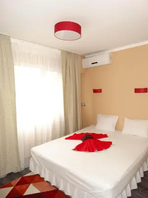 a bedroom with a white bed with a red dress on it at Hotel Simona Complex in Sofia