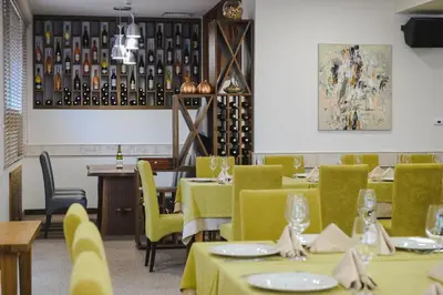 a restaurant with green tables and chairs and wine bottles at Spa Hotel Orbita in Blagoevgrad