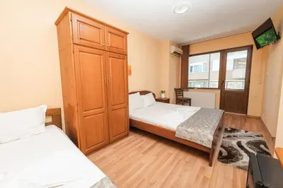 a bedroom with two beds and a large cabinet at Семеен хотел Свети Георги in Sandanski