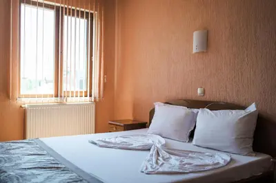 a bedroom with a bed with white pillows and a window at Семеен хотел Свети Георги in Sandanski