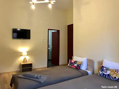 a bedroom with two beds and a tv on the wall at SKYLER GUEST HOUSE in Plovdiv