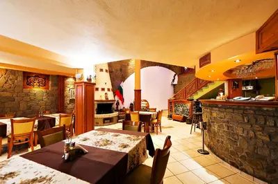 a restaurant with tables and chairs and a stone wall at Family Hotel Ogi in Asenovgrad