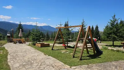 a playground with a swing set in a park at Панорама Стойките Уют in Stoykite