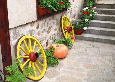 a pumpkin sitting next to a yellow wooden wagon wheel at Guest House Bolyarka in Koprivshtitsa