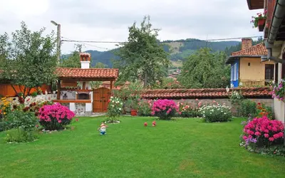 a yard with flowers and a small child in the grass at Guest House Bolyarka in Koprivshtitsa