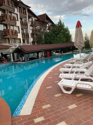 a row of white lounge chairs next to a swimming pool at Belvedere Holiday Club ...VIP ap. in Bansko