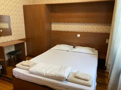 a bedroom with a bed with white sheets and towels at Pop Bogomil family hotel in Sofia