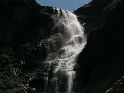 a waterfall on the side of a mountain at Mountain Dreams Apartment in Sapareva Banya