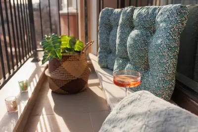 a glass of wine sitting next to a couch on a balcony at К's City Living with Free Parking in Plovdiv