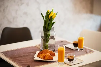 a table with a vase of flowers and orange juice at К's City Living with Free Parking in Plovdiv