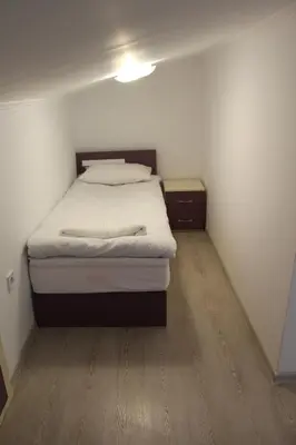 a small bedroom with a bed and a wooden floor at Къща за гости Мишурови in Smolyan