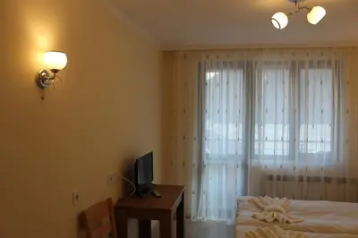 a bedroom with a bed and a desk with a television at Къща за гости Мишурови in Smolyan