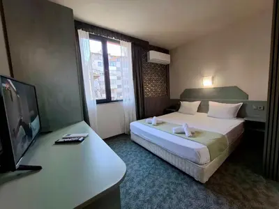 a hotel room with a bed and a flat screen tv at Korona Hotel in Blagoevgrad