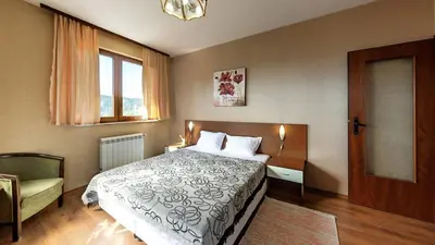 a bedroom with a bed and a chair and a window at Family Hotel Emaly 1 in Bankya