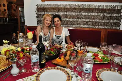 two women sitting at a table with food and wine at Family Hotel Emaly 2 in Sapareva Banya