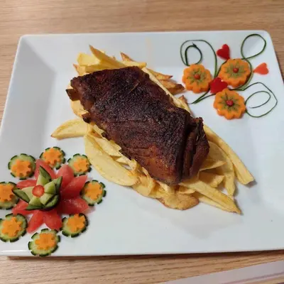 a plate of food with a piece of meat and chips at Family Hotel Emaly 2 in Sapareva Banya