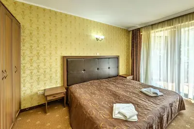 a bedroom with a large bed with two towels on it at Хотел Магнолия, Hotel Magnoliya in Panichishte