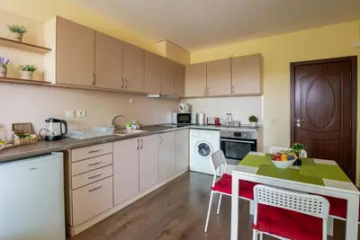 a kitchen with white cabinets and a table with chairs at RIVERSIDE APARTMENTS PLOVDIV with free parking in Plovdiv