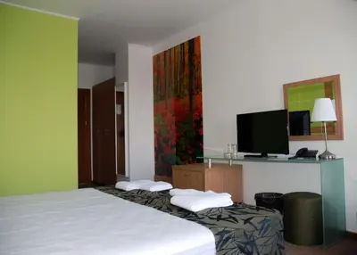 a hotel room with a bed with a tv on the wall at Green Hisar Hotel Family in Hisarya