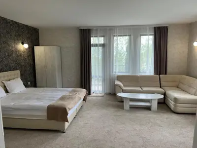a bedroom with a bed and a couch and a table at Chiflika Family Hotel in Asenovgrad